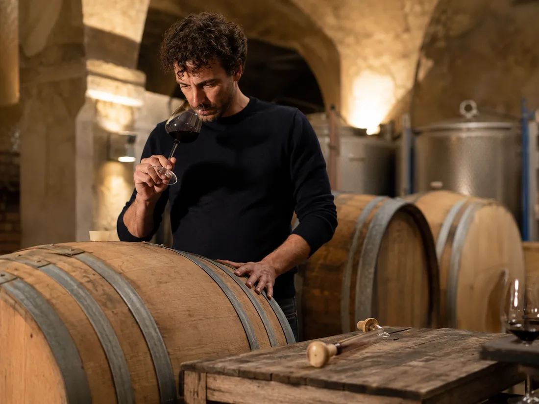 Winemaker tasting wine from a cellar barrel in a low-intervention winemaking setting